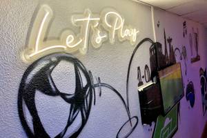 Eine Wand mit Graffiti, einem Fußball und der Beschriftung 'Let's Play'.