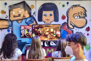 Kinder spielen ein Videospiel vor einer Wand mit bunten Graffiti im Principal Afilliated by RH Hotel.