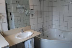 Ein Badezimmer mit Badewanne, Spiegel und Waschbecken im Hotel Principal Afilliated by RH.
