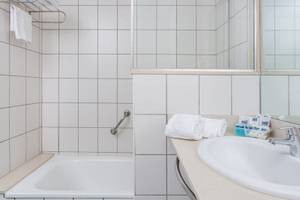 Modernes Badezimmer mit einer Dusche, Badewanne, Handtuchhalter und Waschbecken.