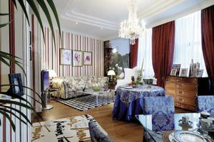 Wohnzimmer im Westin Valencia mit blauen und weißen Mustern, Kristallkronleuchter und rote Vorhänge.