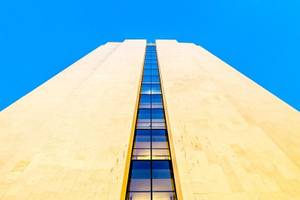 Ein hohes Gebäude mit Glasfenstern gegen einen blauen Himmel