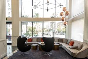 Lobby des Exe Rey Don Jaime Hotels mit moderner Einrichtung und großen Fenstern.