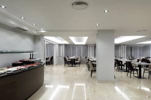 Frühstücksbuffet im Exe Rey Don Jaime Hotel mit vielen Tischen und Stühlen.