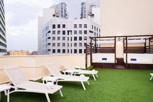Dachterrasse des Exe Rey Don Jaime Hotels mit weißen Liegestühlen und grünem Kunstrasen.