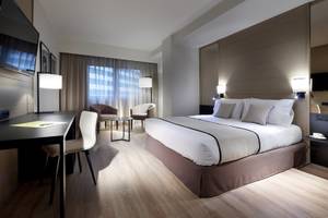 Innenansicht eines Hotelzimmers im Exe Rey Don Jaime, mit Bett, Schreibtisch und Stühlen.