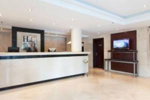 Empfangsbereich des Valencia Center Hotels mit moderner Rezeptionstheke und digitalem Empfangsbereich.