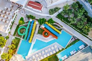 Luftaufnahme des Schwimmbads im Lindos Royal Resort mit mehreren Wasserrutschen und Sonnenliegen.