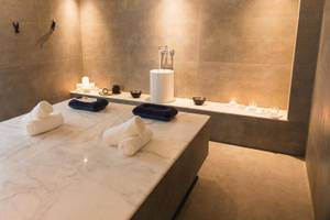 Spa-Behandlungsraum im Lindos Royal Resort mit Marmortisch und blauen Kissen.