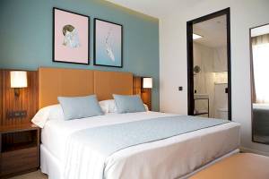 Schlafzimmer im Riu Plaza Espana Hotel mit einem großen Bett und zwei Bildern an der Wand.
