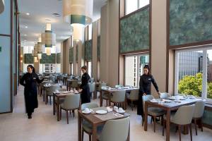Restaurant im Riu Plaza Espana mit drei Kellnerinnen und gedeckten Tischen