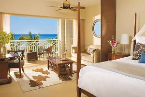 Gemütliche Suite im Secrets St. James Hotel mit Meerblick, Bett, Wohnzimmer und Balkon.