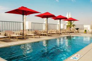 Pool-Terrasse des Riu Plaza Espana Hotels mit roten Sonnenschirmen und Liegen.