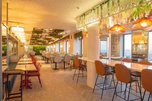 Innenbereich des Riu Plaza Espana Restaurants mit Tischen, Stühlen und grünen Pflanzen an der Decke.
