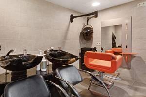 Friseursalon im ALUA Gran Camp de Mar mit modernen Stühlen und Waschbecken.
