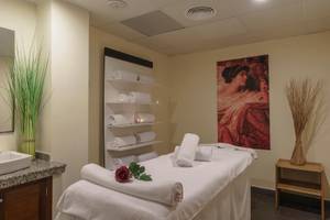 Spa-Behandlungsraum im ALUA Gran Camp de Mar mit Massageliege, Toilettenartikeln und Wanddekoration.