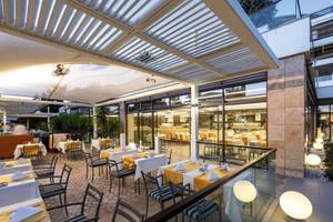 Restaurantterrasse des TUI BLUE Side Hotels mit gedeckten Tischen und Stühlen unter einem Sonnendach.