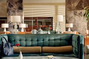 Lobby des TUI BLUE Side Hotels mit grünem Sofa, Tisch und Blumenvase.