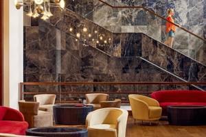 Lobby-Bereich des TUI BLUE Side Hotels mit Marmorwänden, einer Treppe und verschiedenen Sitzmöbeln.