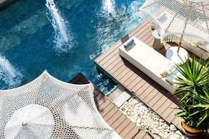 Pool-Terrasse im TUI BLUE Side Hotel mit weißen Sonnenschirmen und einer grünen Pflanze.