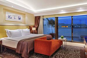Schlafzimmer im TUI BLUE Side Hotel mit großem Bett, rotem Sessel und Panoramafenstern.