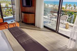 Zimmer im TUI BLUE Side Hotel mit Blick auf das Meer und eine Terrasse mit Möbeln.