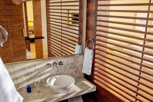 Badezimmer im TUI BLUE Side Hotel mit Waschbecken, Spiegel und Holzjalousien.