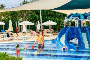 Mann und Kind spielen im Wasser am Pool im Magic Life Jacaranda Hotel
