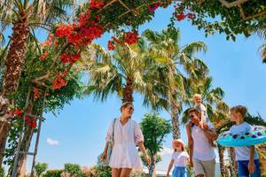 Familie spaziert unter Palmen im Magic Life Jacaranda Hotel