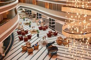 Hotellobby des Magic Life Jacaranda mit Klavier, Kristallleuchte und Loungemöbeln.