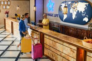 Rezeption im Magic Life Jacaranda Hotel mit Mitarbeitern und Gästen, die Gepäck haben.