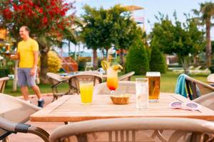 Terrasse im Magic Life Jacaranda Hotel mit Getränken und einem Mitarbeiter.