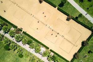 Luftaufnahme des Sandplatzes im Magic Life Jacaranda mit mehreren Spielern und umliegenden Grünflächen.