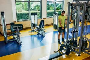 Ein Mann im gelben T-Shirt steht im Fitnessbereich des Magic Life Jacaranda Hotels.