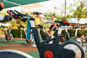 Fitnessräder unter einem Dach im Freien, mit zwei Personen, die sie benutzen