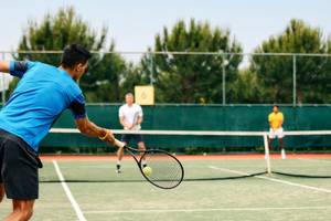 Tennisspieler im Magic Life Jacaranda schlagen den Ball über das Netz.