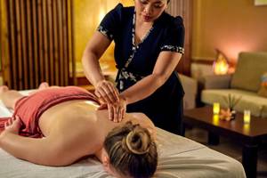 Eine Frau erhält eine Massage in einem Hotel, während eine Therapeutin sie massiert.