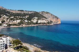 Aussicht auf das Canyamel Classic Hotel und die Bucht mit blauem Meer und grünem Hügel.