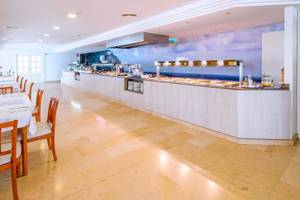Innenansicht des Restaurants im Canyamel Classic Hotel mit Tisch, Stühlen und Buffet.