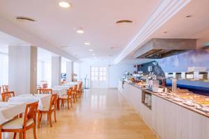 Frühstücksbereich des Canyamel Classic Hotels mit Tisch, Stühlen und Buffet.