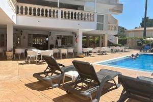 Außenbereich des Canyamel Classic Hotels mit Pool, Liegestühlen und Tischen.