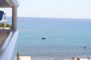 Aussicht vom Balkon auf das Meer mit einem Boot und einem Paar, das badet.