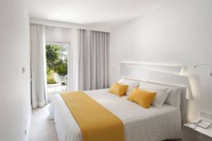 Hotelzimmer im Paraiso de los Pinos mit Bett, gelber Bettdecke, weißem Kopfteil und Zugang zur Terrasse.