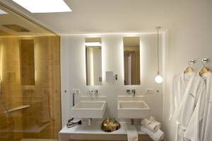 Badezimmer im Paraiso de los Pinos Hotel mit zwei Waschbecken, einer Dusche und weißen Handtüchern.