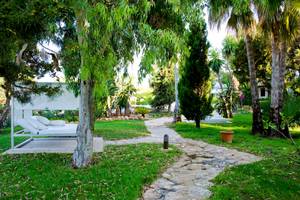 Gartenlounge des Paraiso de los Pinos Hotels mit weißen Möbeln und einem Pfad