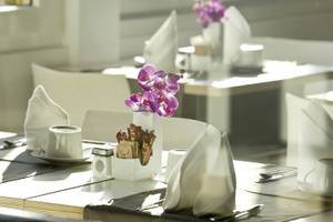 Ein gedeckter Tisch im Restaurant des Tahiti Hotels mit einer Orchidee in einer Vase.