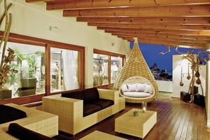Lounge-Bereich des Tahiti Hotels mit Rattan-Sofas, Tisch und Hängesessel.