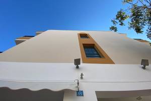 Außenansicht des Rosales Formentera Hotels mit weißer Fassade und braunen Fensterrahmen.