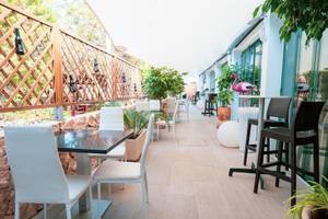 Rosales Formentera Hotel Terrasse mit weißen Stühlen, Tischen und Pflanzen.