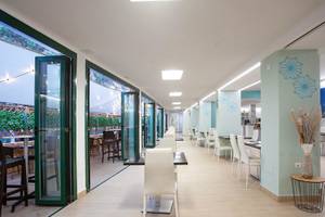 Rosales Formentera Hotelspeisesaal mit weißen Stühlen und Tischen, beleuchteten Decken und großen Fenstern.